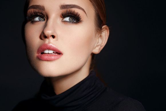 A close up of a woman 's face with long eyelashes and a black turtleneck.