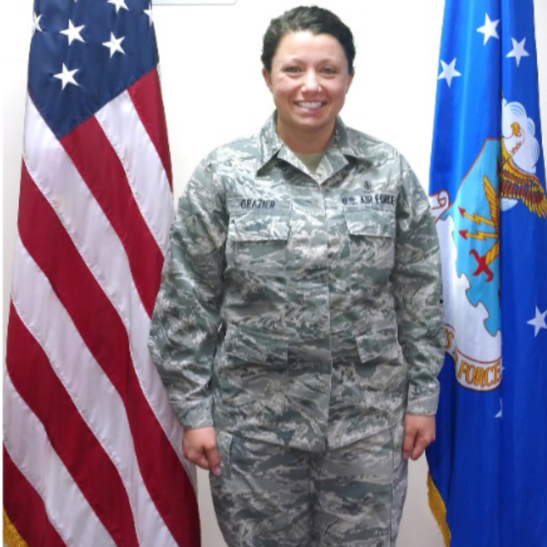 Woman in Air Force uniform stands between American and Air Force flags.