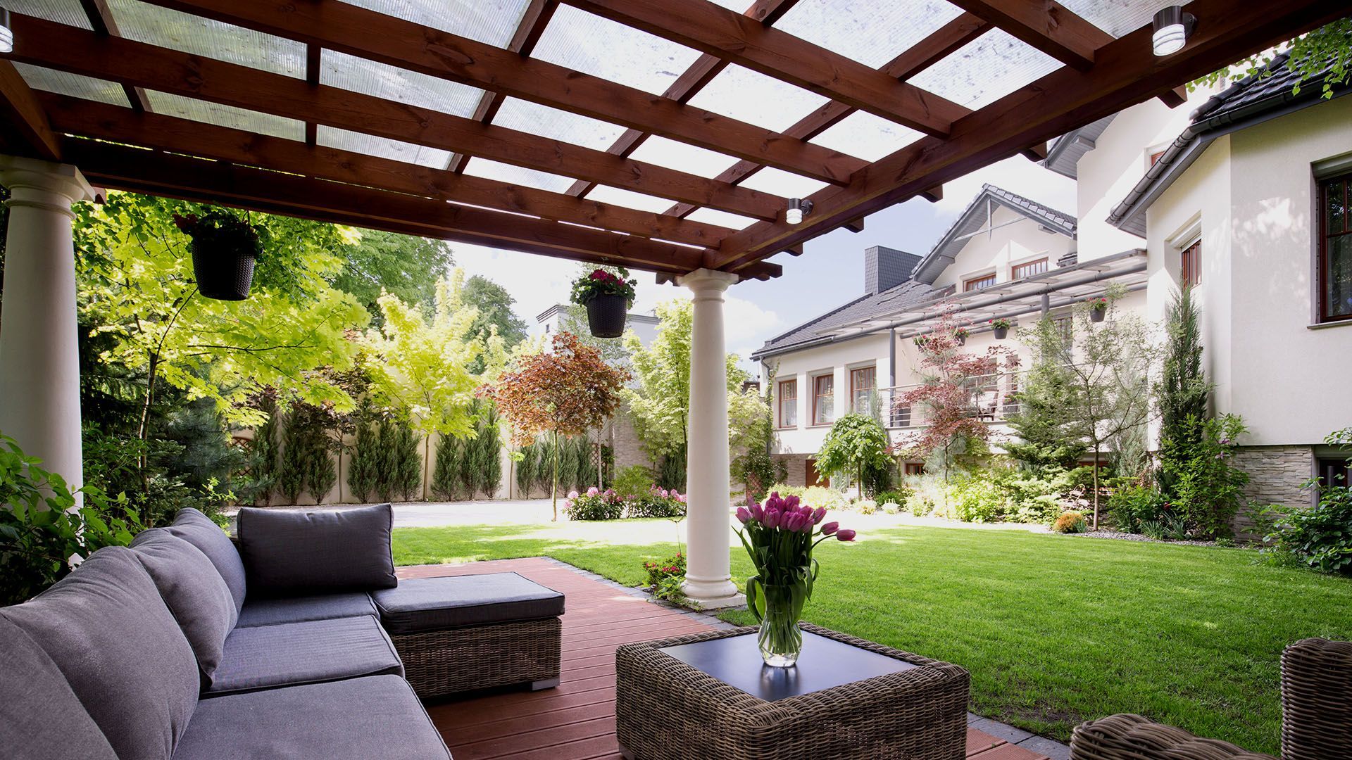 A patio with a couch , chairs and a table under a pergola.