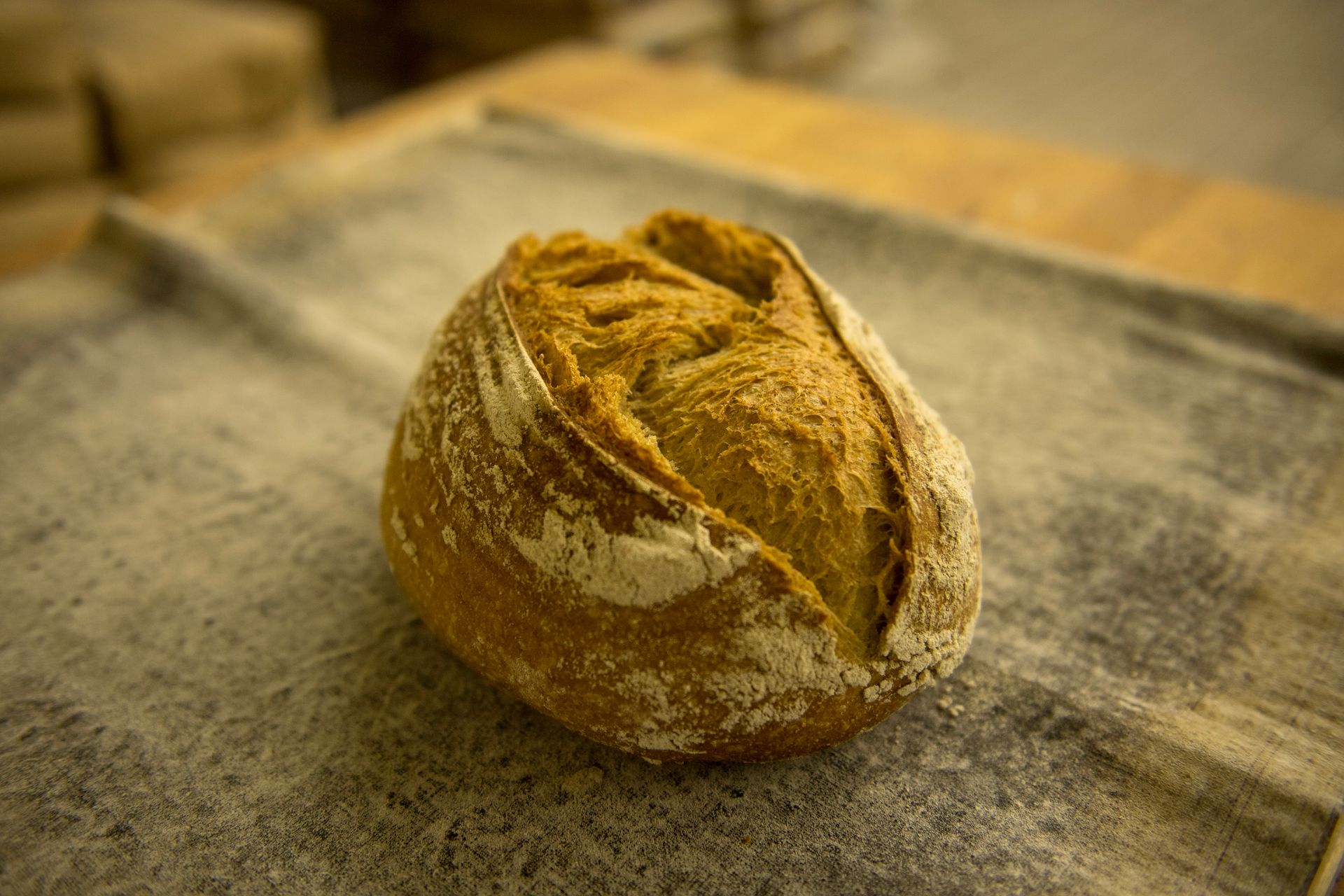 A loaf of bread is sitting on a towel on a table.