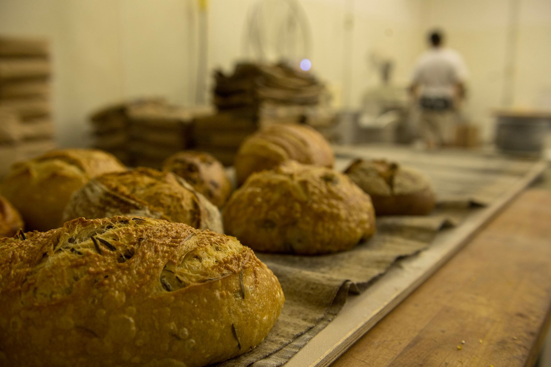 A bunch of bread is sitting on a wooden table in a bakery.