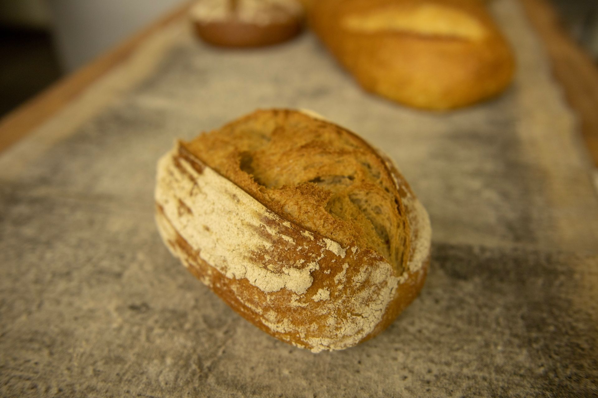 A loaf of bread is sitting on a table covered in flour.