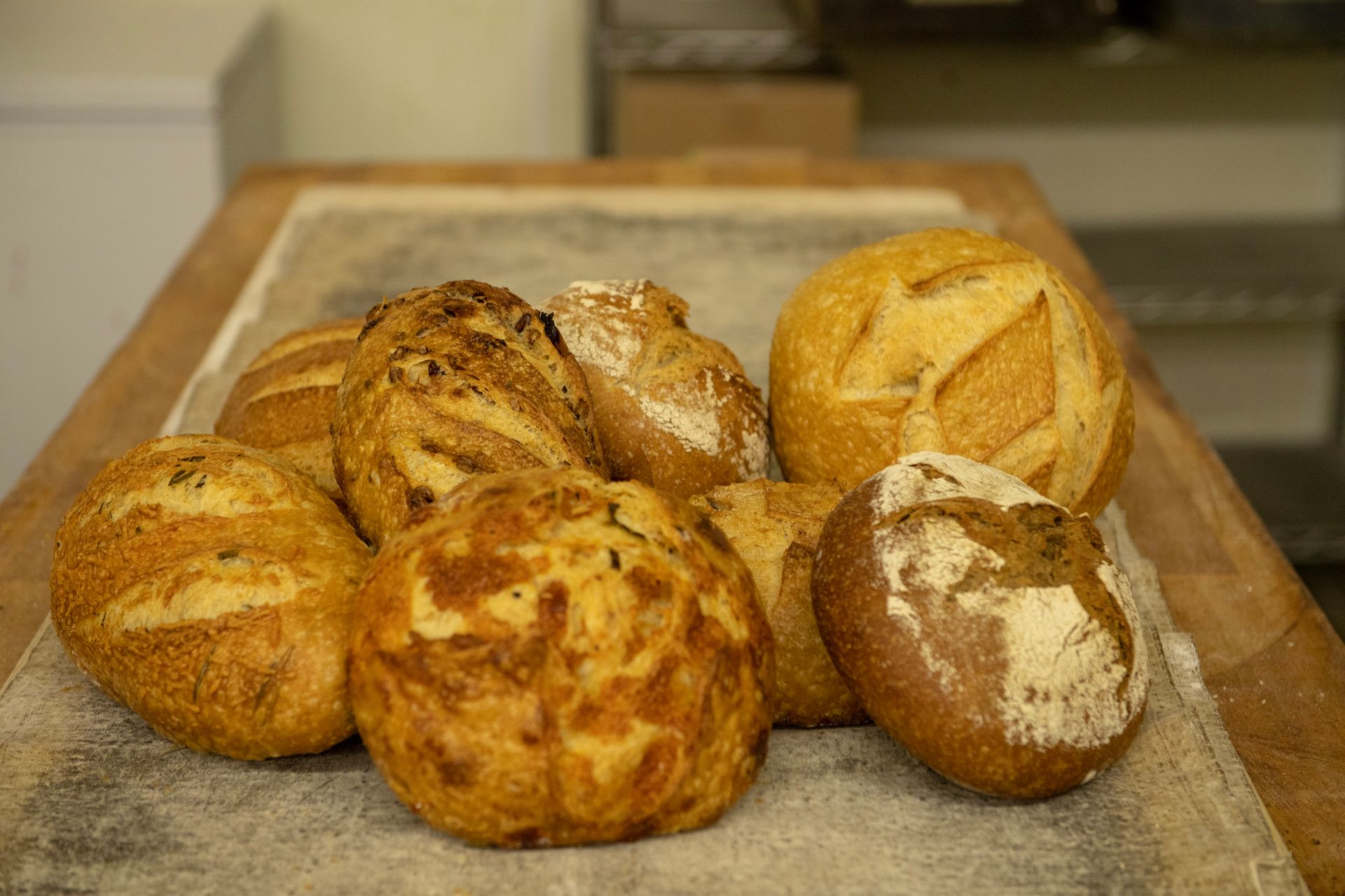 A bunch of different types of bread are sitting on a wooden table.