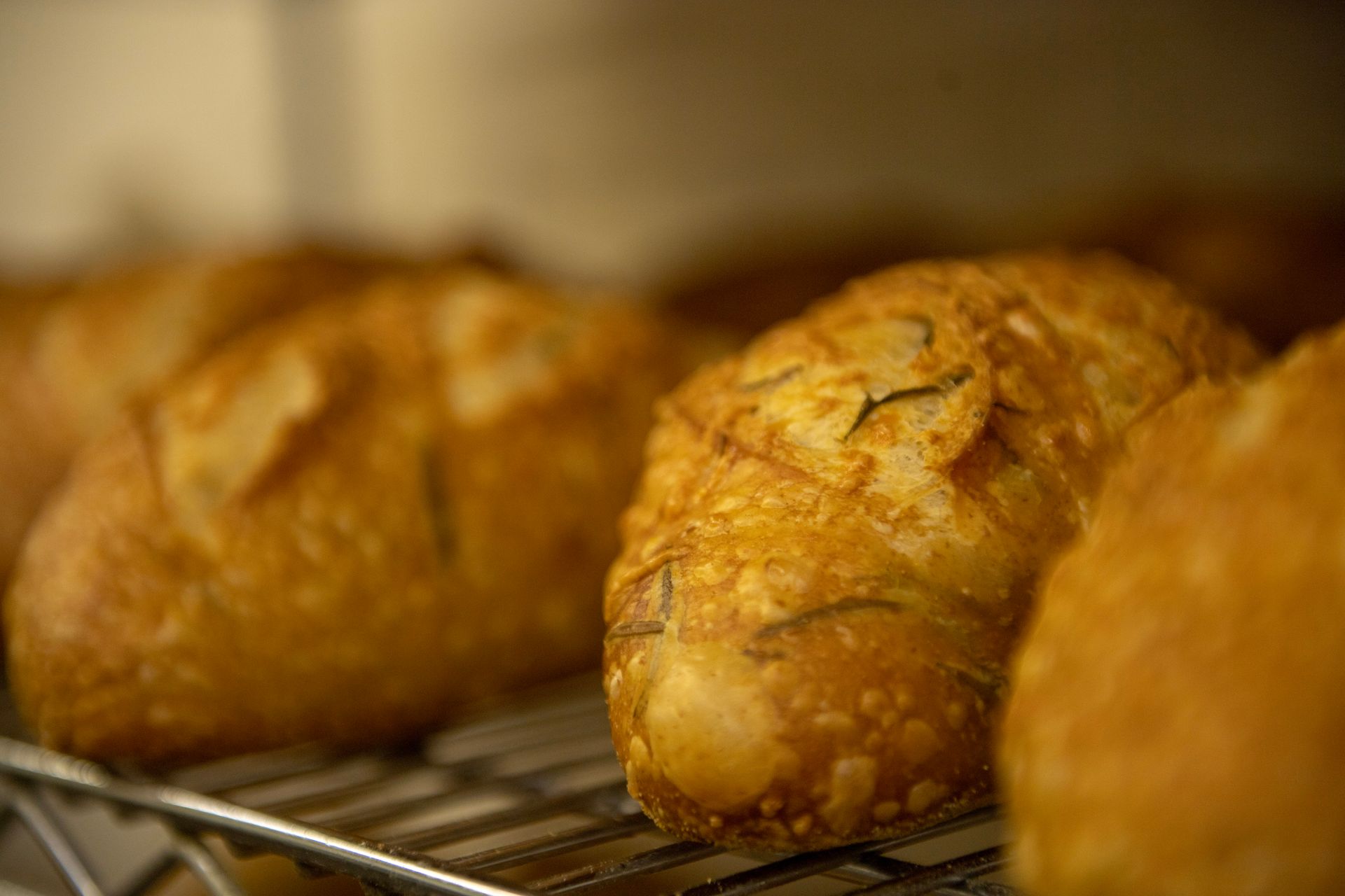 A bunch of bread is sitting on a cooling rack.
