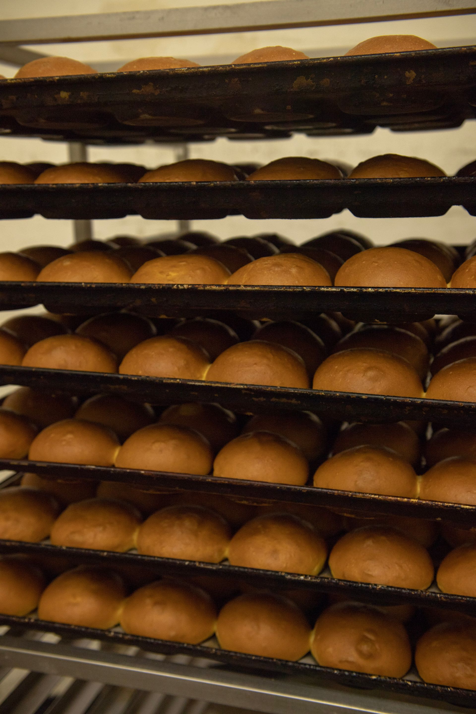 A bunch of buns are sitting on a rack in a bakery