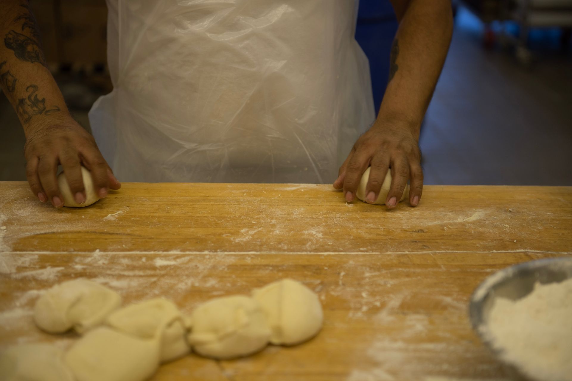 A person is kneading dough on a wooden table.