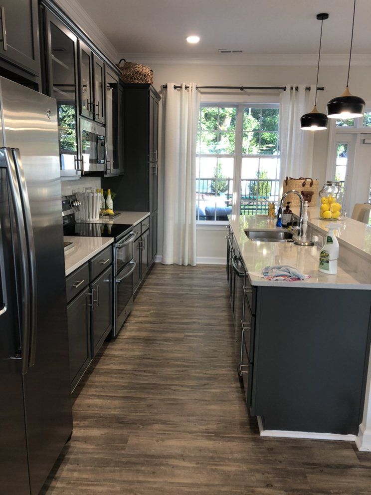 Modern kitchen with gray cabinets, stainless steel appliances, and an island with a sink.