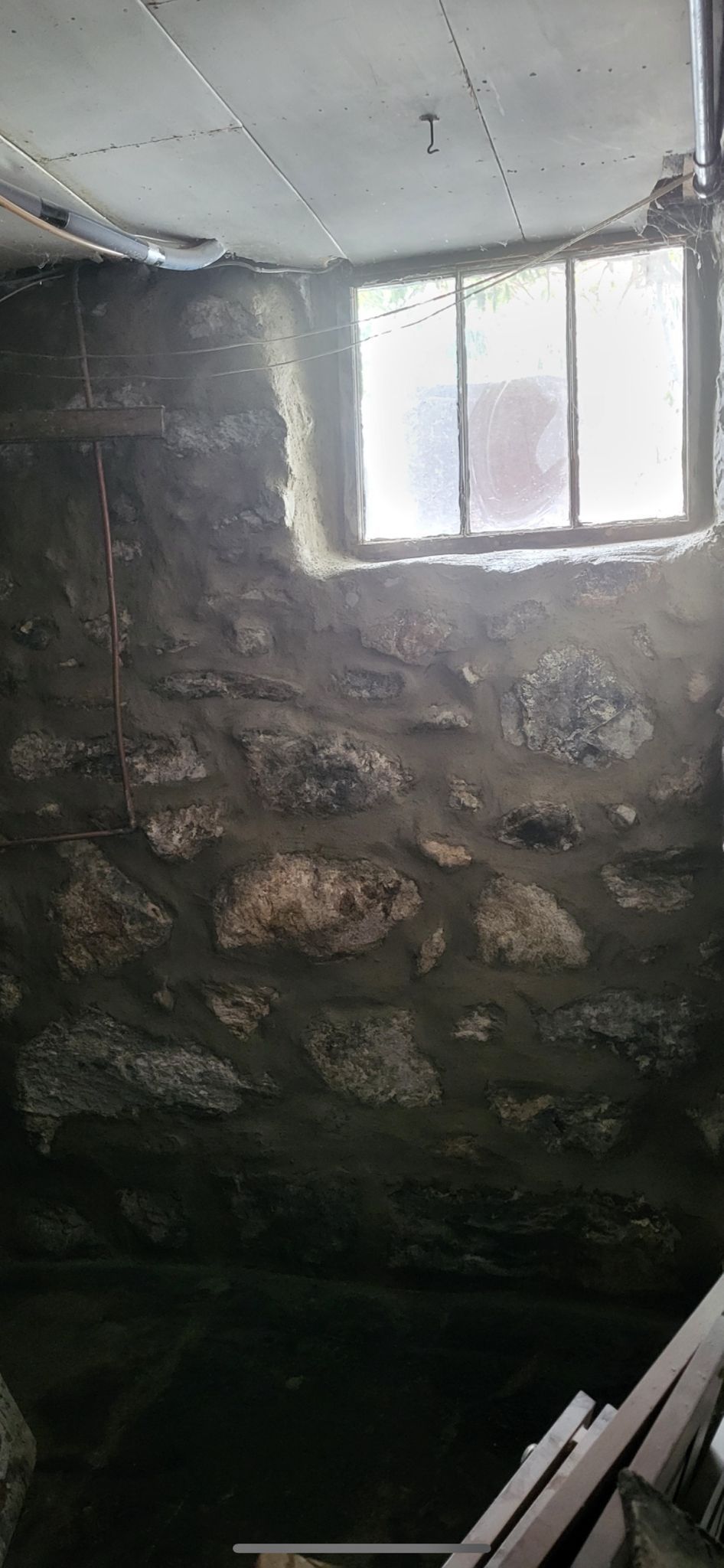 A room with a stone wall and a window in it.