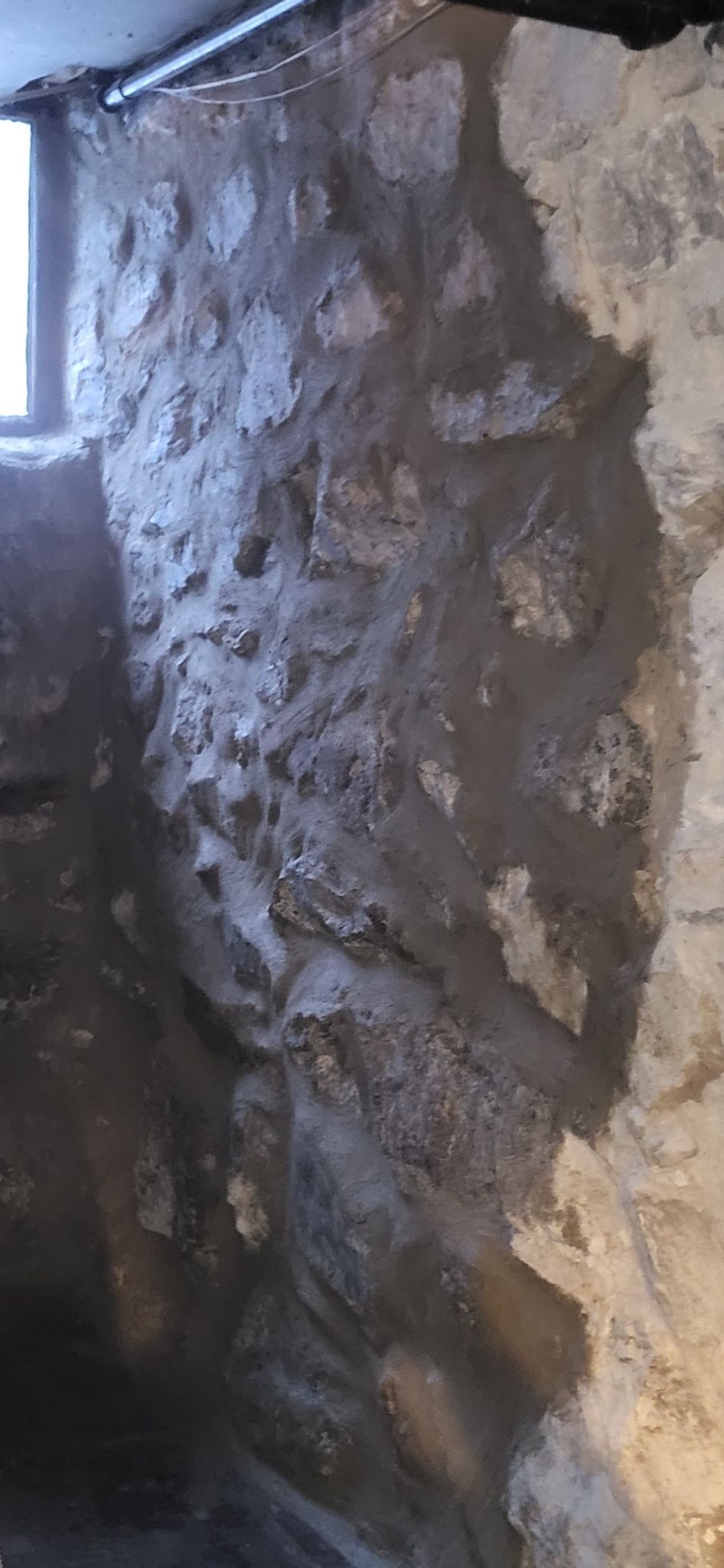 A room with a stone wall and a window.