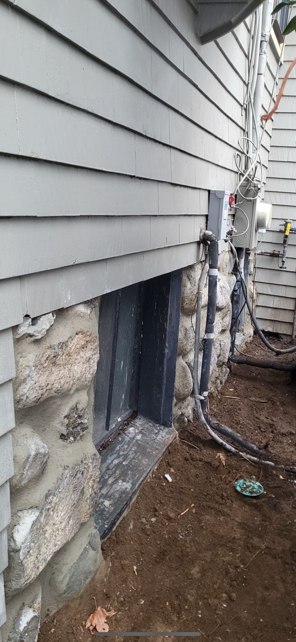 The side of a house with a window in the foundation.