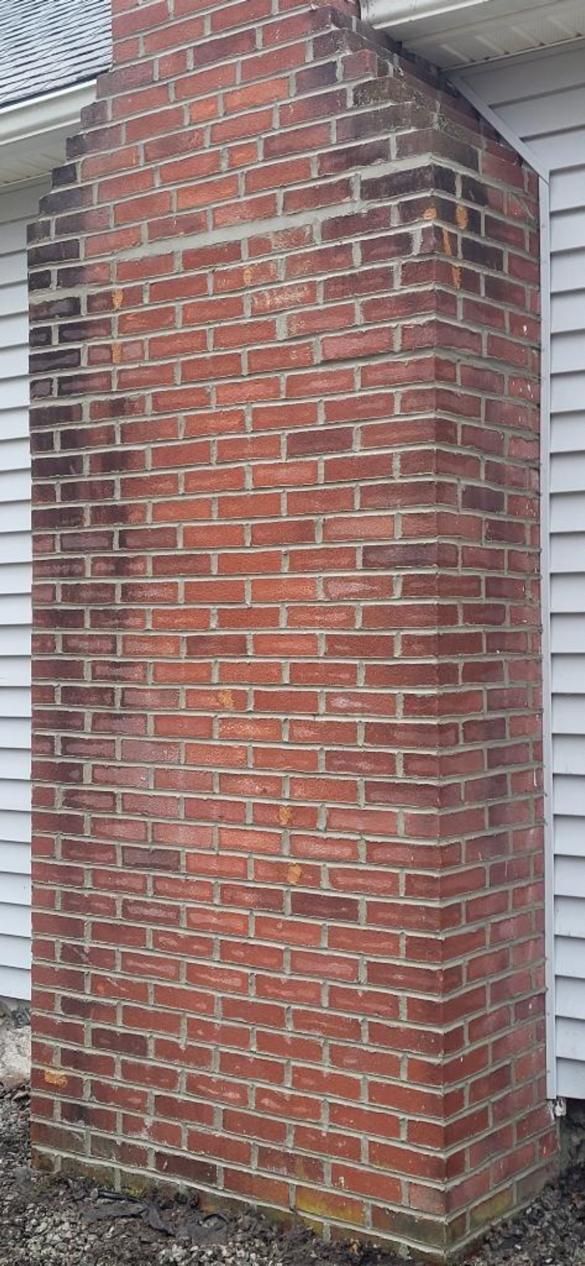 A large brick chimney is sitting on the side of a house.