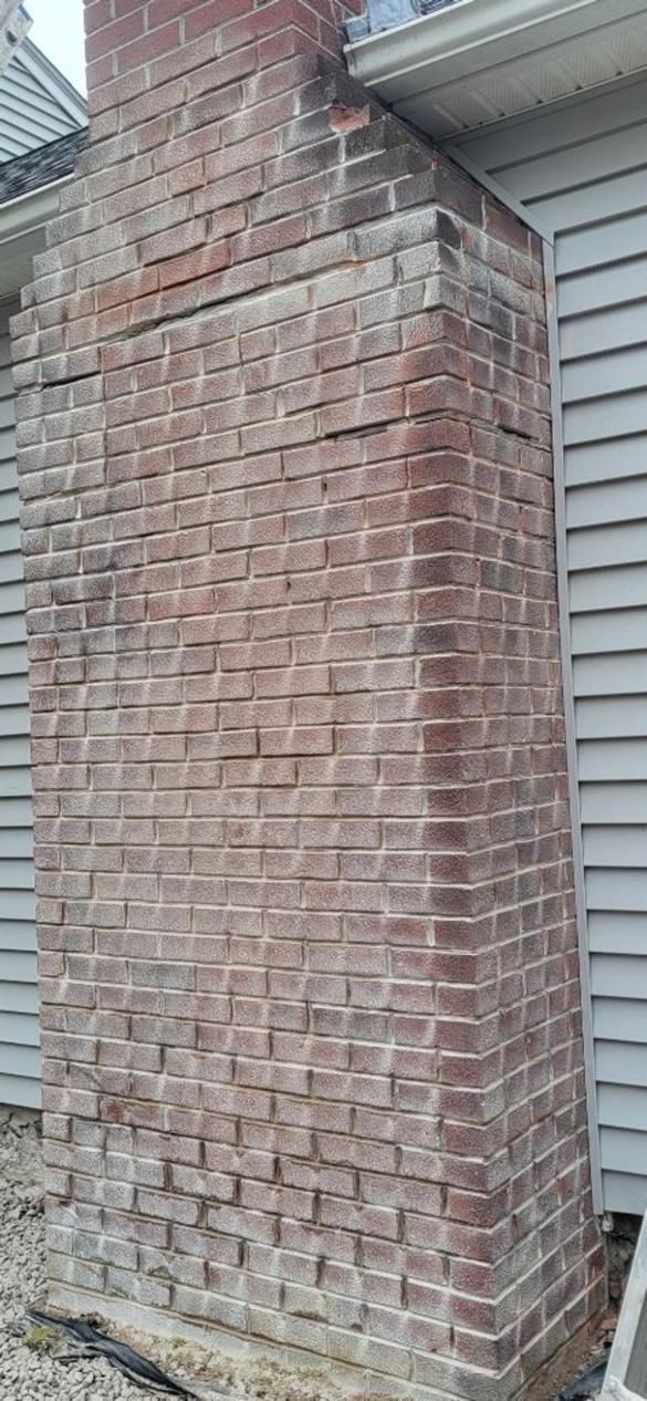 A large brick chimney is sitting on the side of a house.