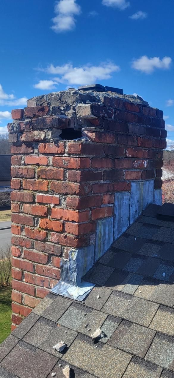 A brick chimney is sitting on top of a roof.