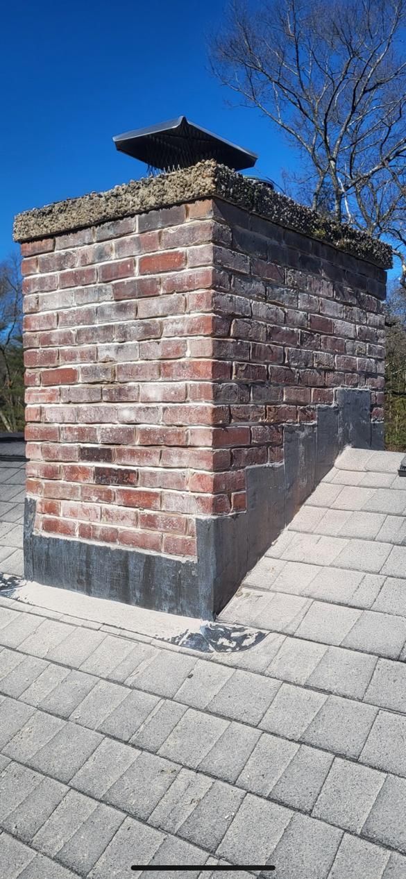A brick chimney is sitting on top of a brick roof.