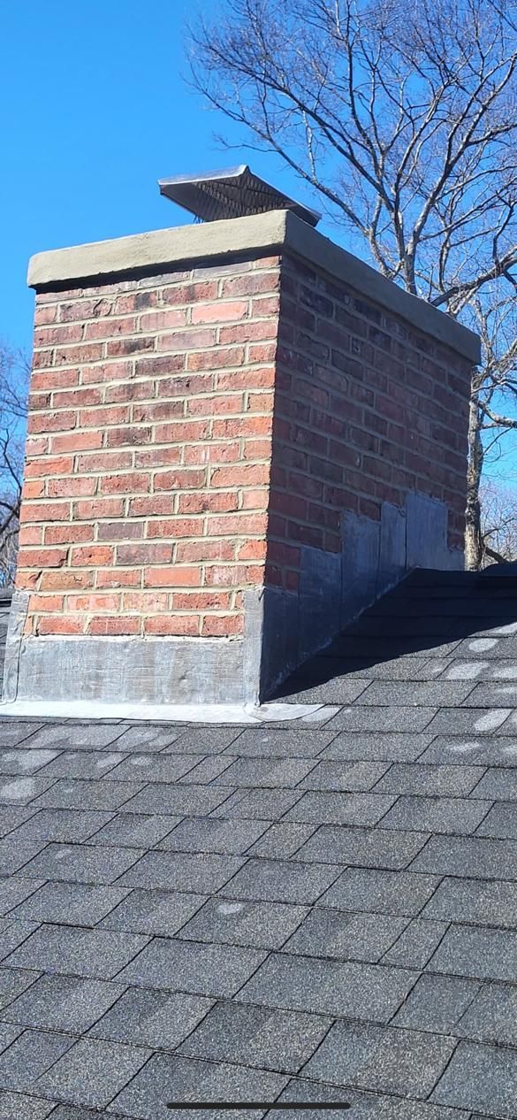 A brick chimney is sitting on top of a roof.
