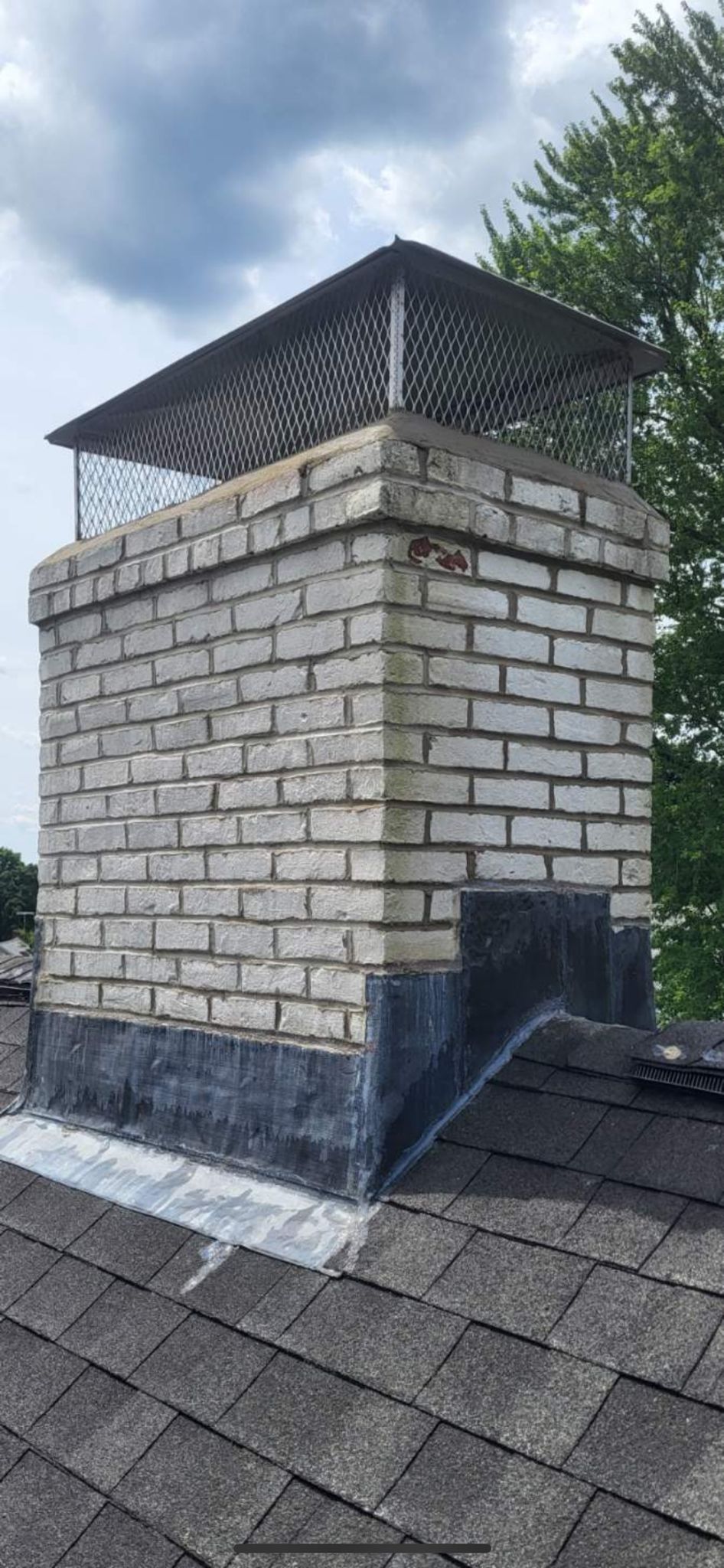 A brick chimney is sitting on top of a roof.