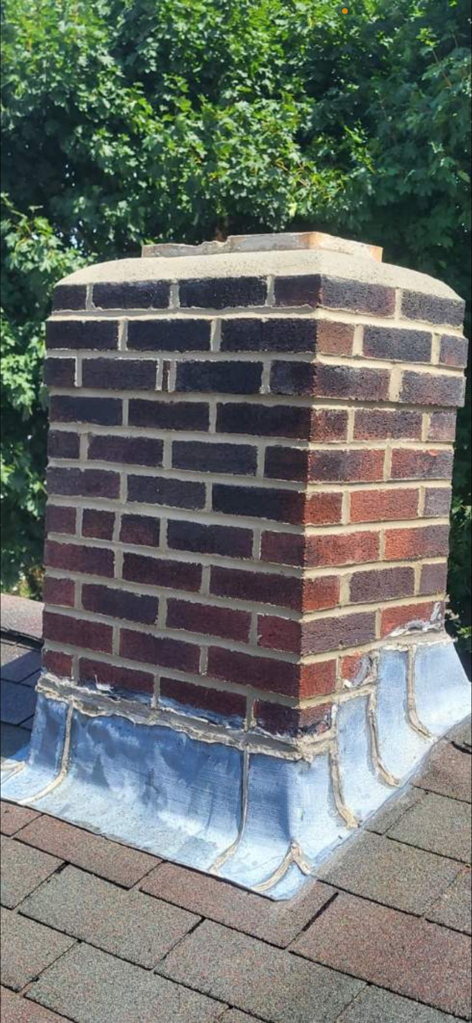 A brick chimney is sitting on top of a roof.