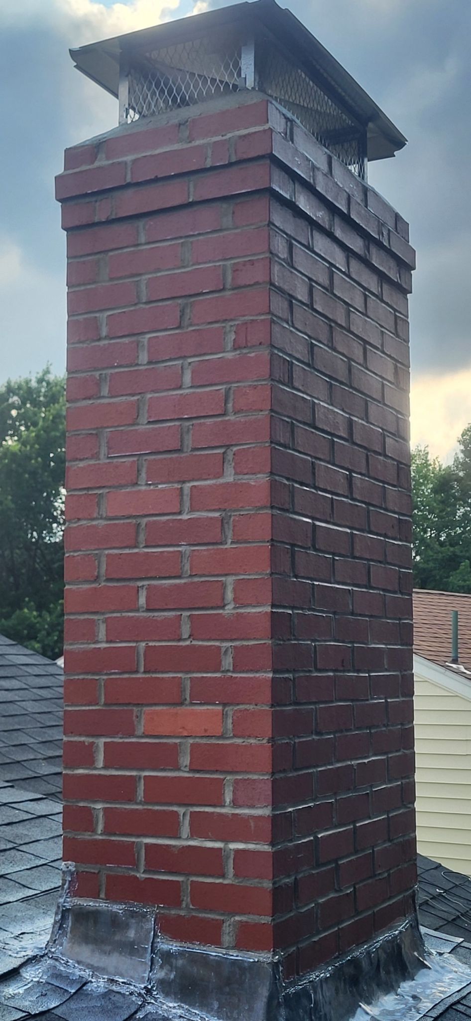 A red brick chimney is sitting on top of a roof.