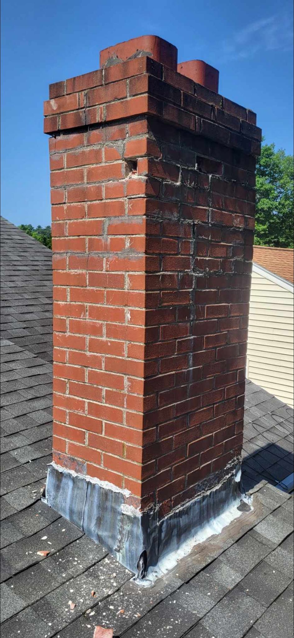 A brick chimney is sitting on top of a roof.