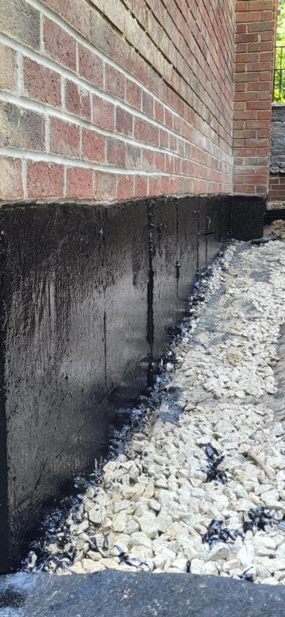 A close up of a brick wall with gravel in front of it.