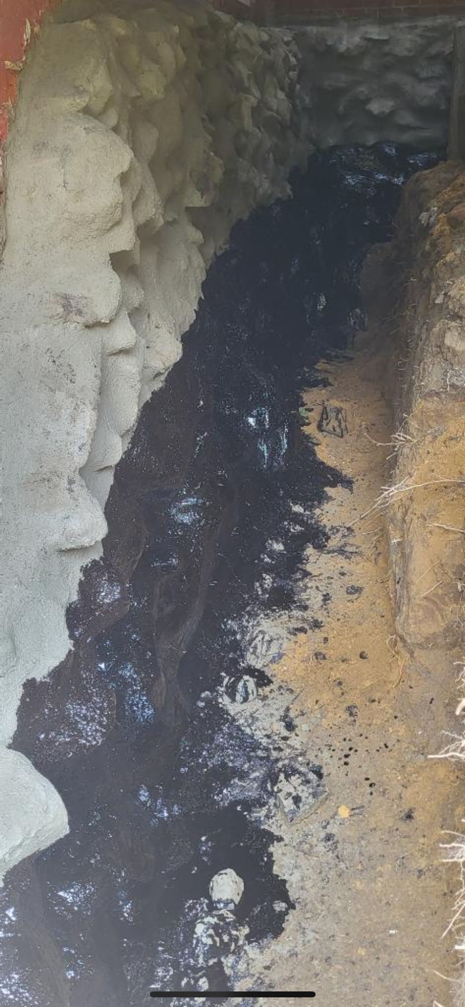 A close up of a hole in the ground with a lot of dirt and water coming out of it.