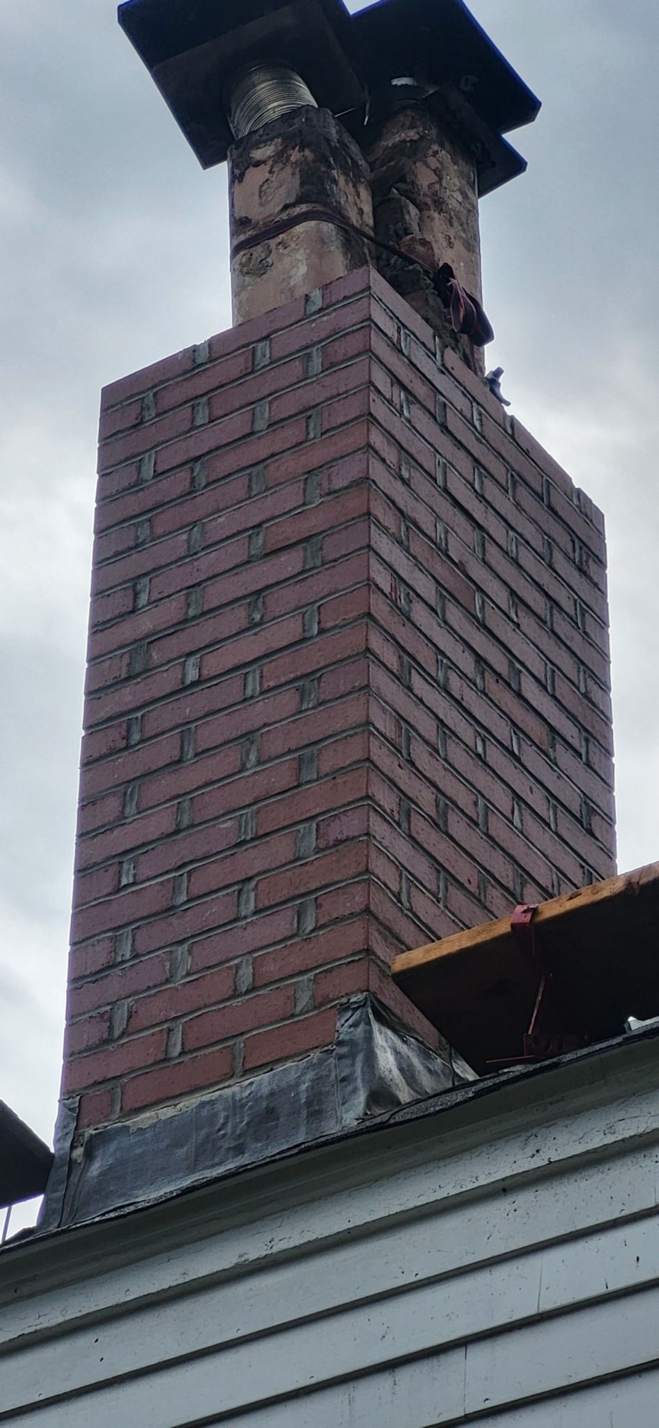 A brick chimney is sitting on top of a white house.