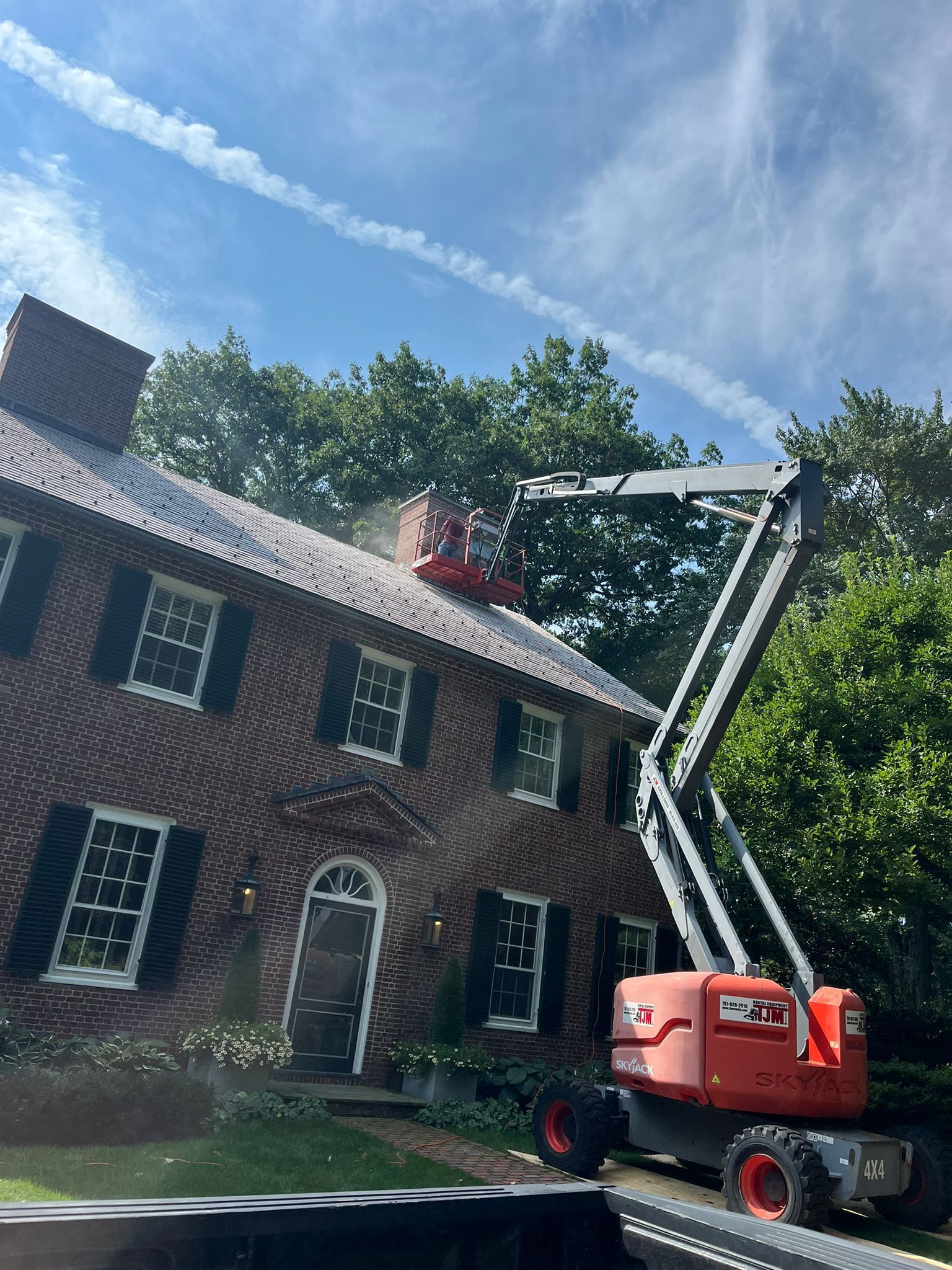 A crane is cleaning the roof of a brick house.
