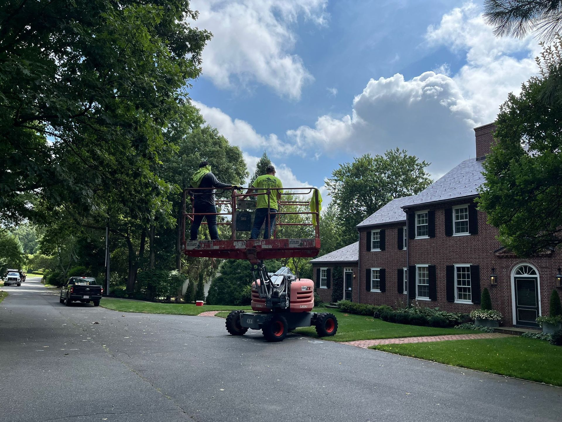 A man is sitting on a lift in front of a brick house.