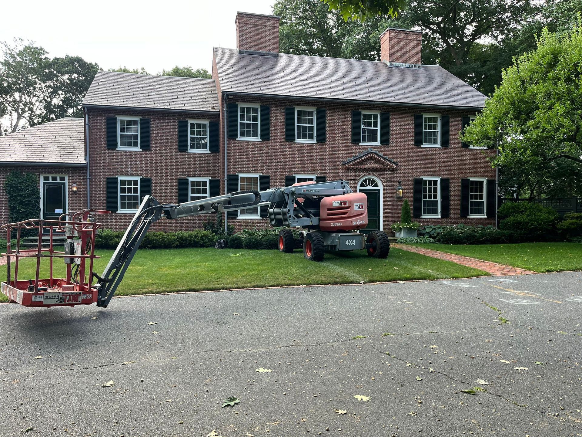 A tractor is parked in front of a large brick house.