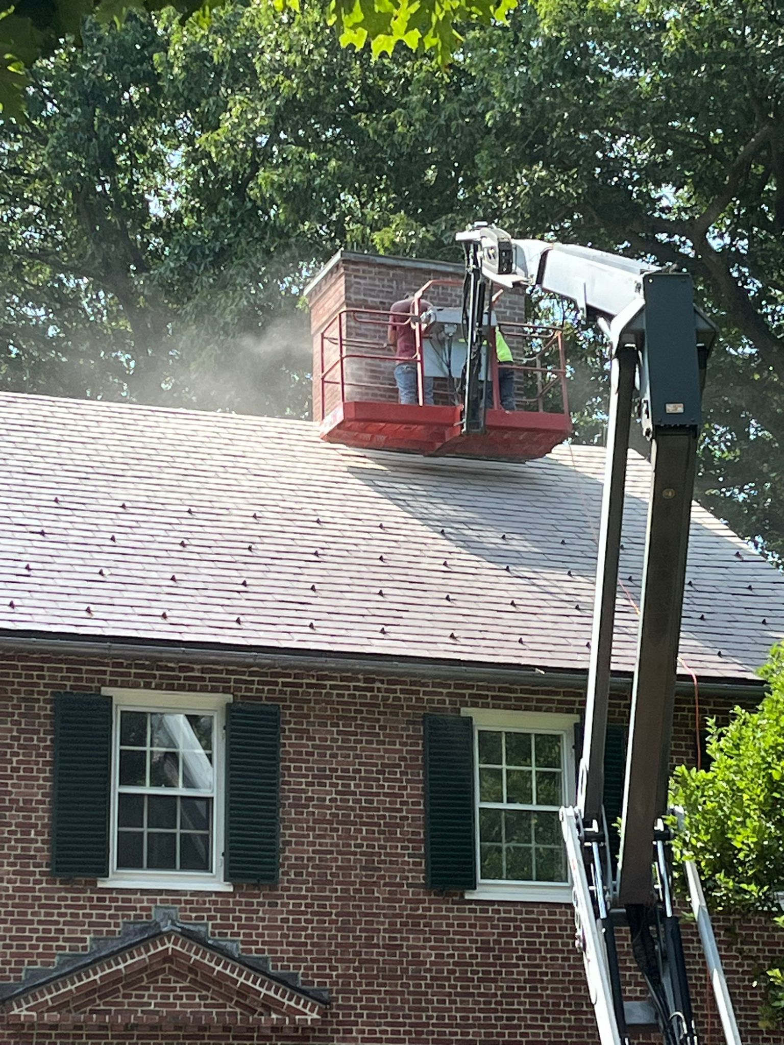 A crane is cleaning the roof of a brick house.