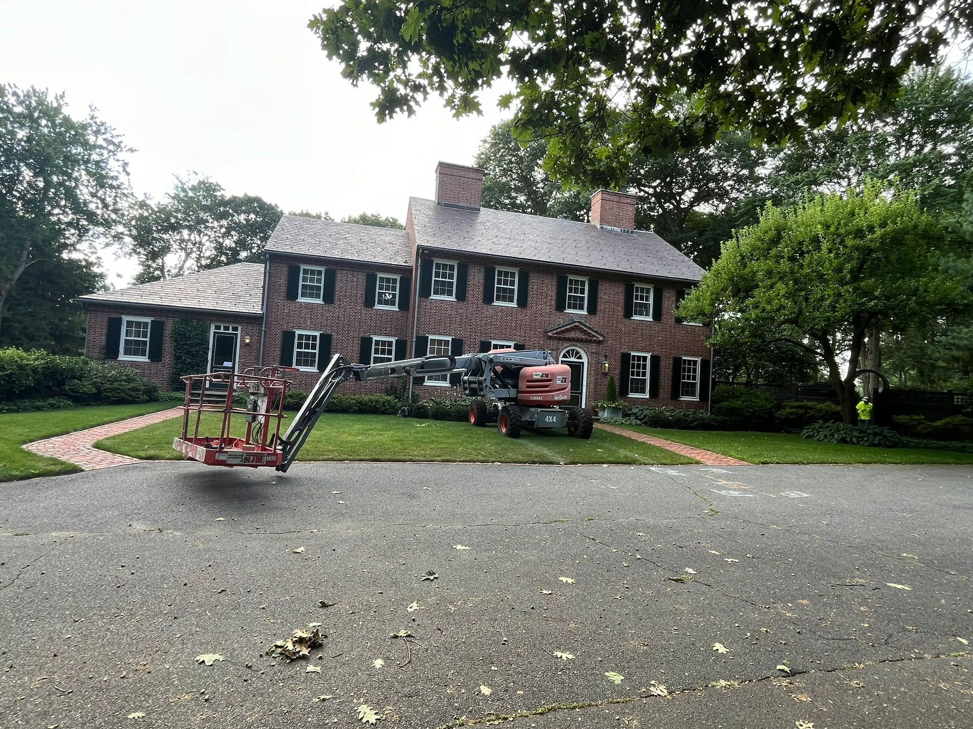 A large brick house with a lawn mower parked in front of it.