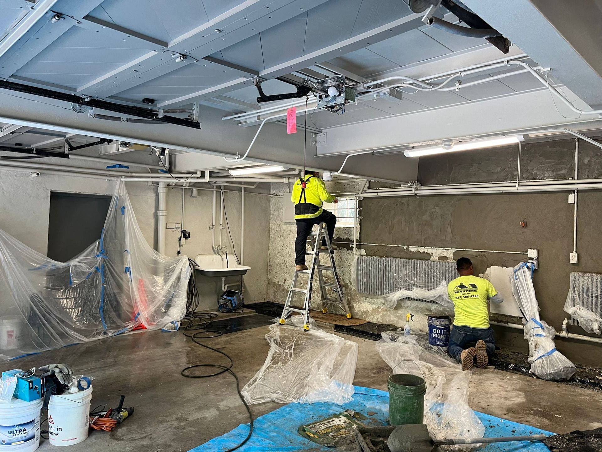 A couple of men are working on a wall in a room.