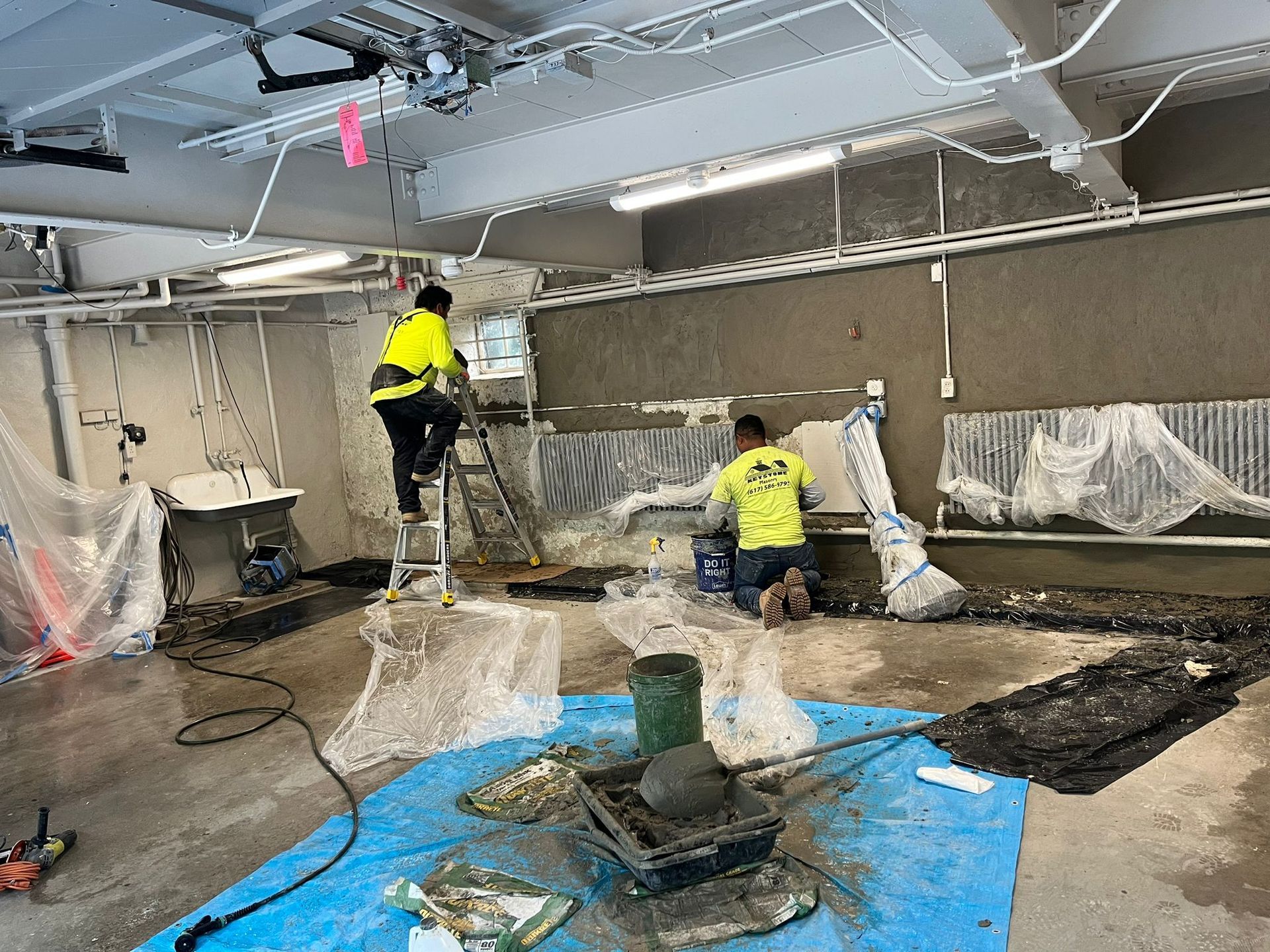 Two men are working on a wall in a room.