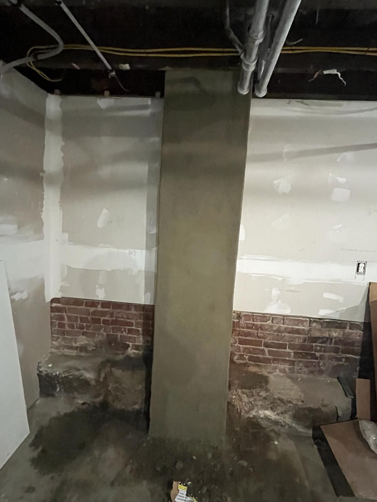 A room with a brick wall and a concrete column in it.