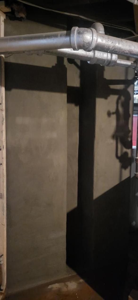 A pipe is hanging from a wall in a basement.