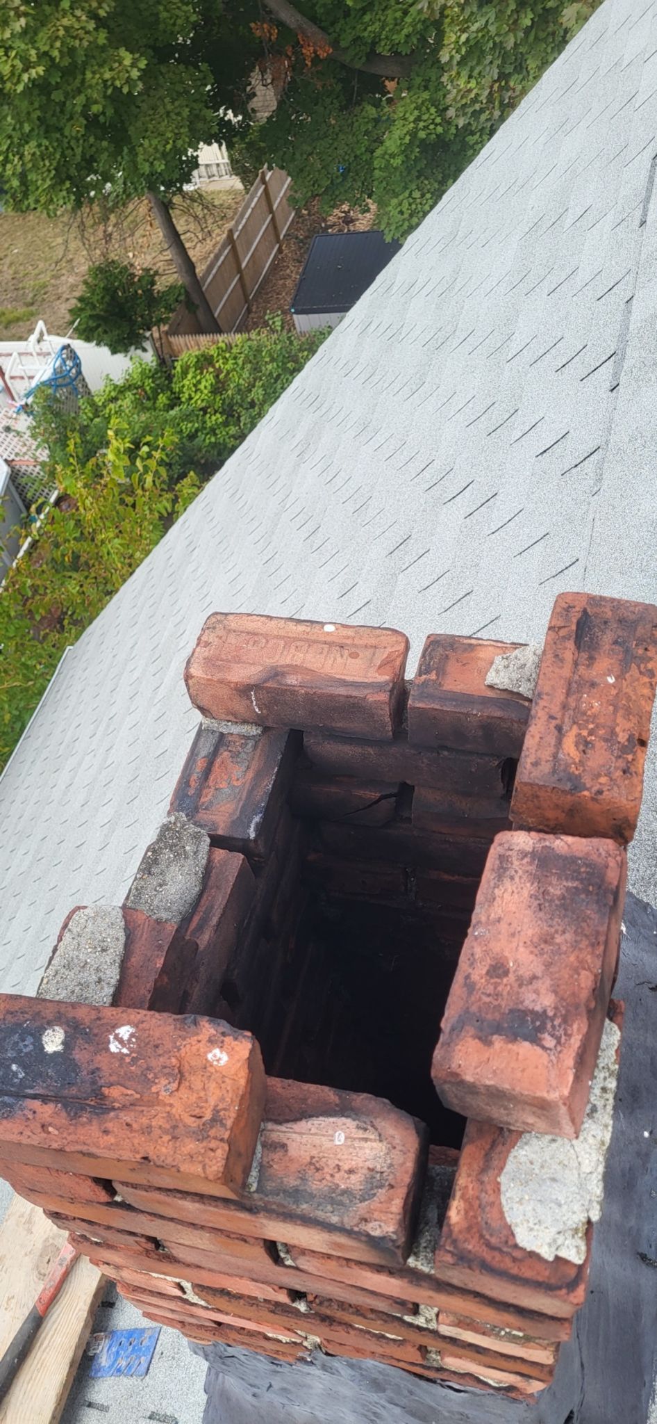 A brick chimney is being built on top of a roof