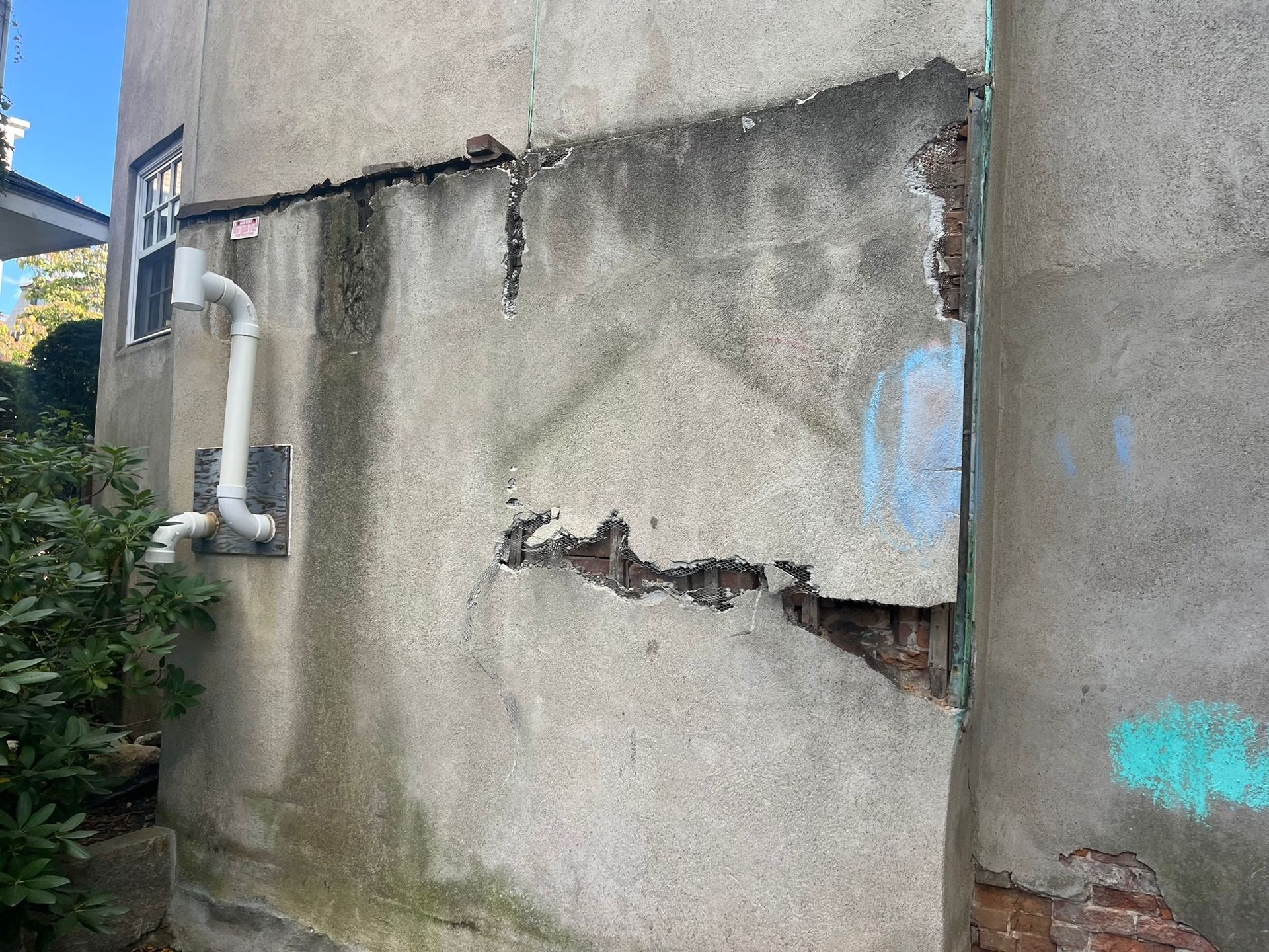 A concrete wall with a hole in it and a pipe coming out of it