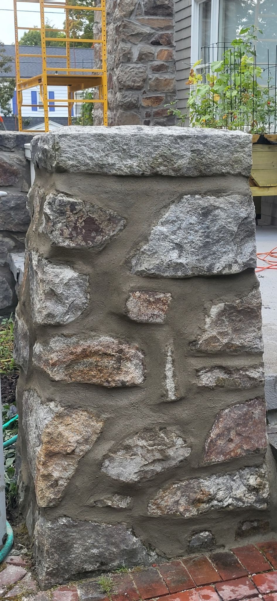 A stone wall with a scaffolding in the background