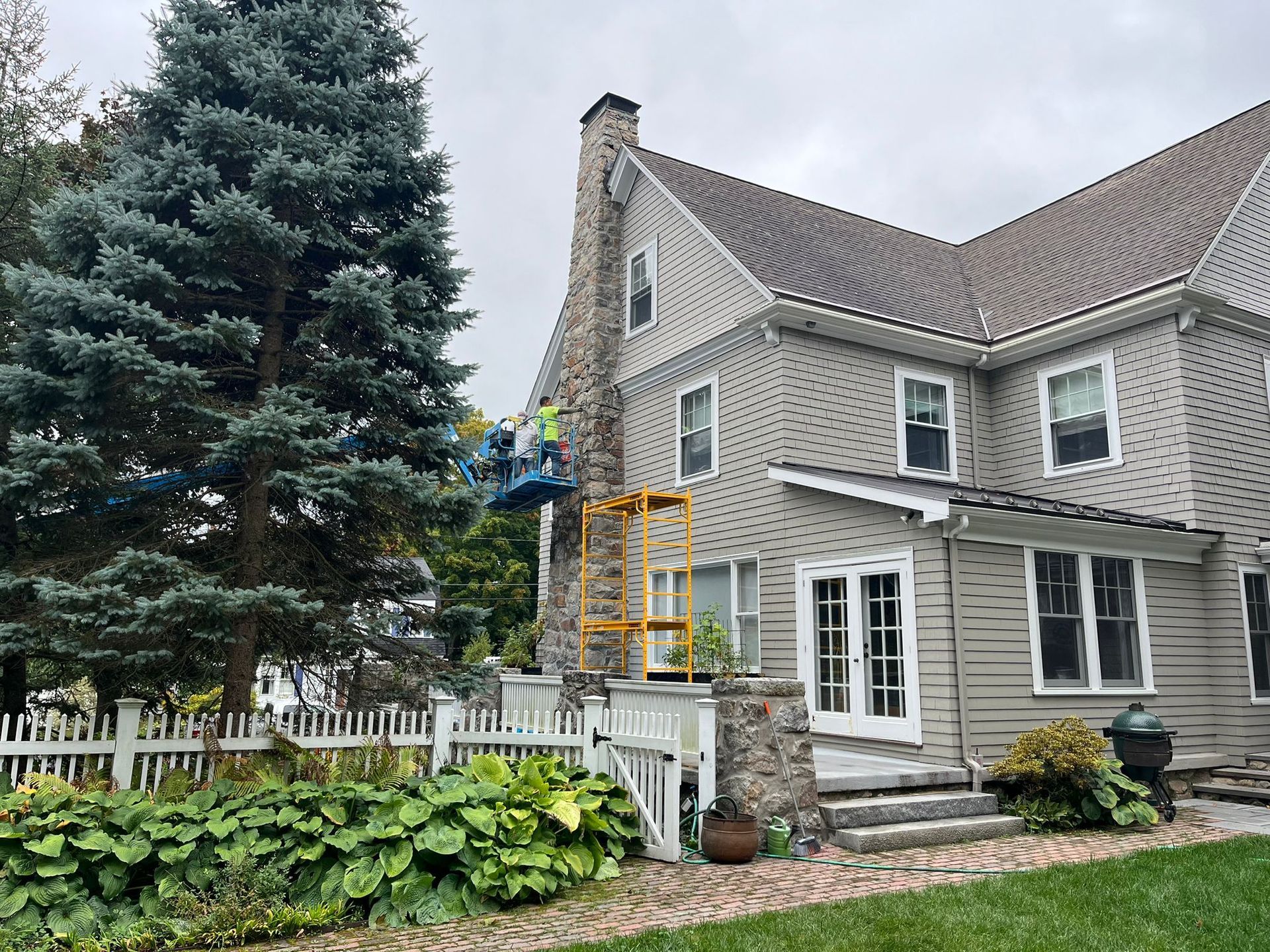 A man is painting the side of a house with a crane