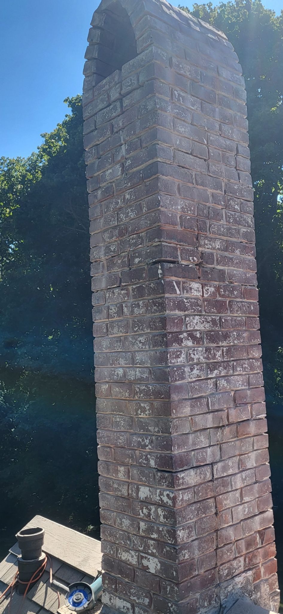A large brick chimney is sitting on top of a roof