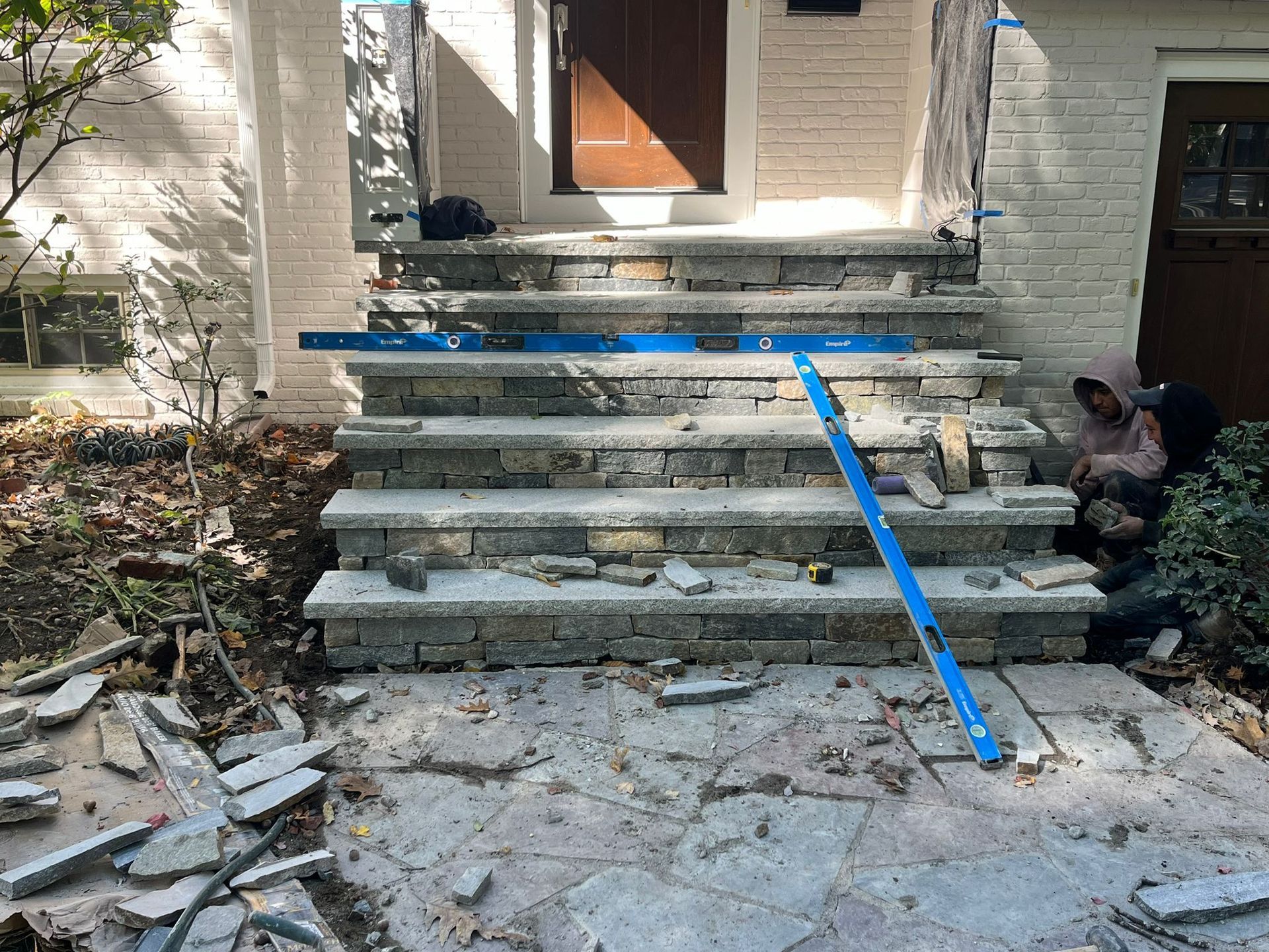 A group of people are working on a set of stairs in front of a house