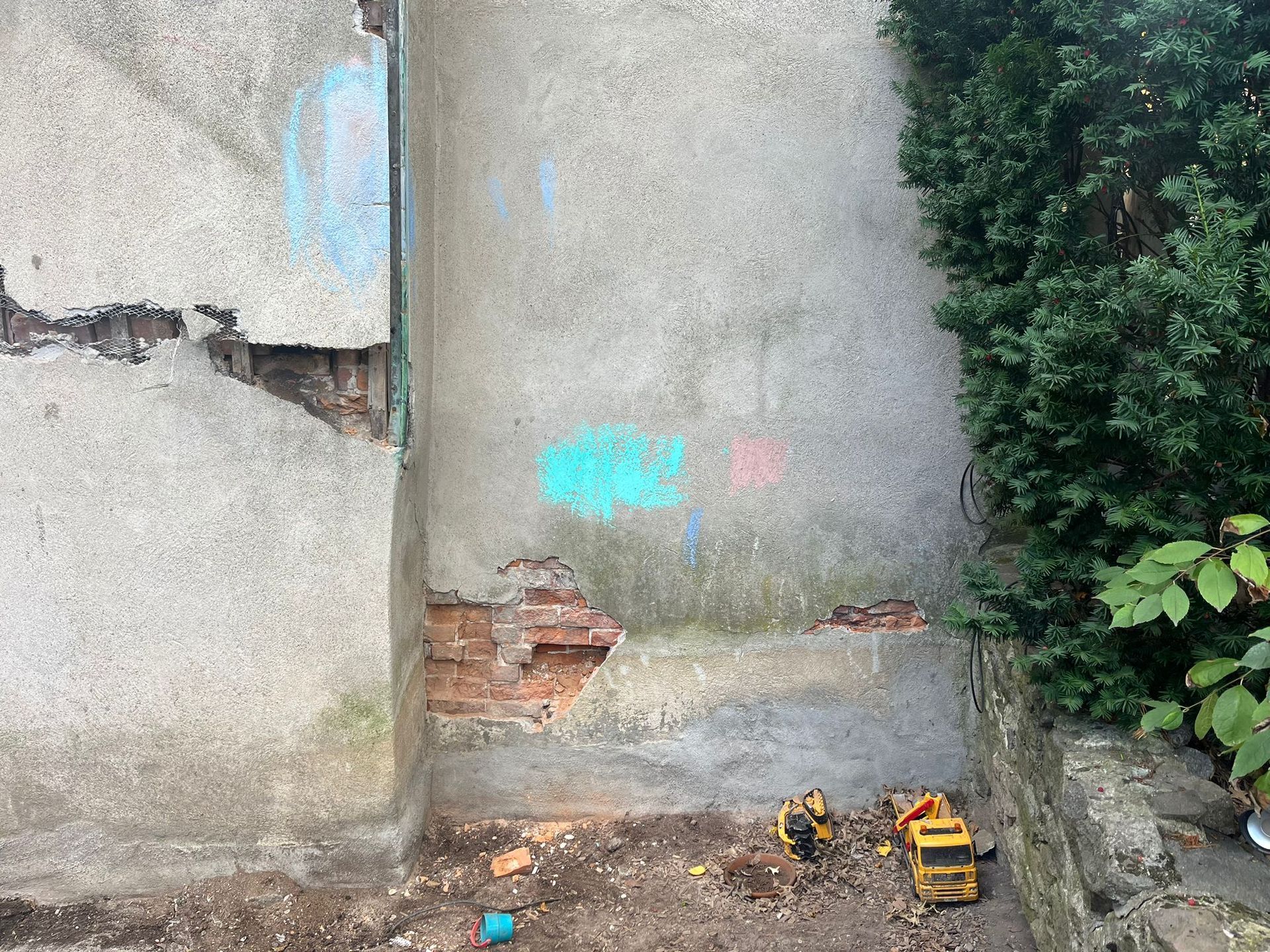 A concrete wall with a hole in it and a tree in the background