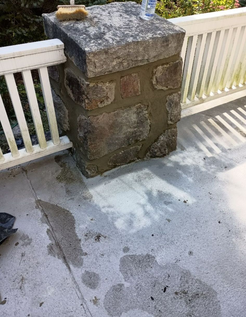 A stone pillar is sitting on the ground next to a white fence