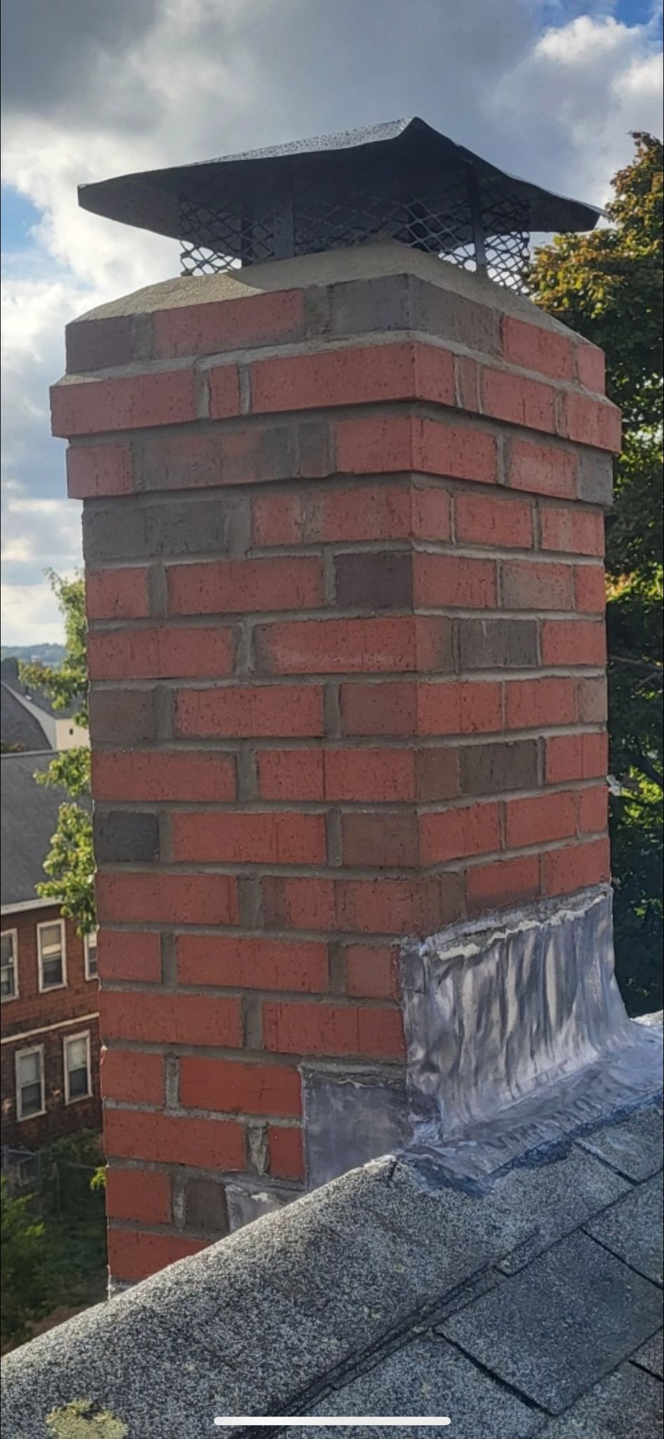 A brick chimney is sitting on top of a roof