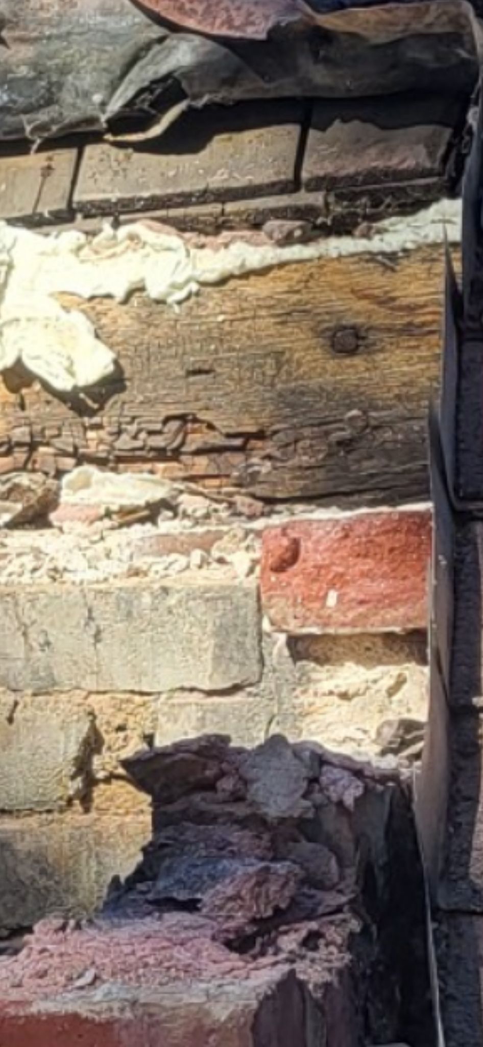 A close up of a brick wall with a roof in the background