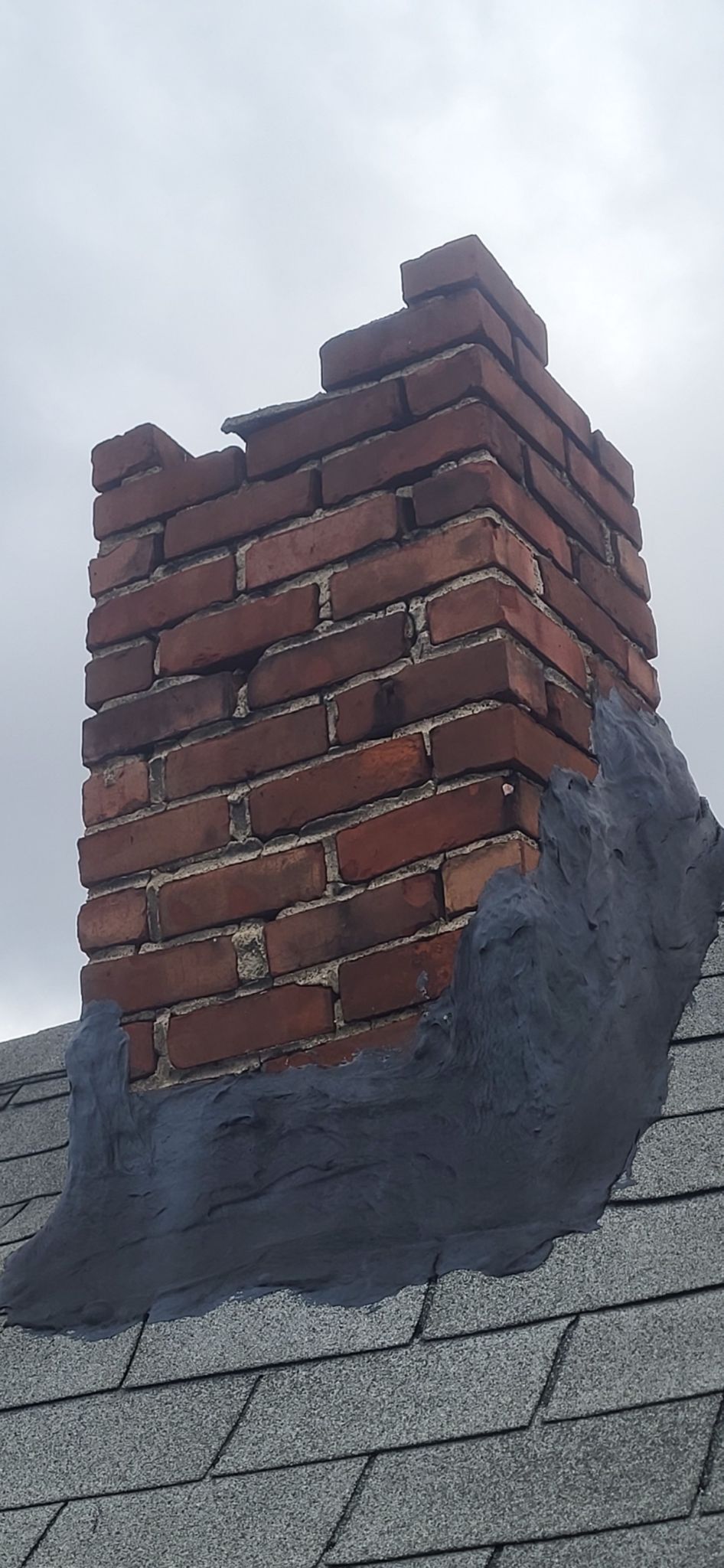 A brick chimney is sitting on top of a roof