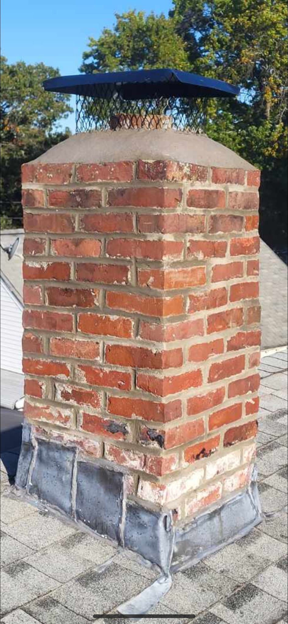 A brick chimney is sitting on top of a roof