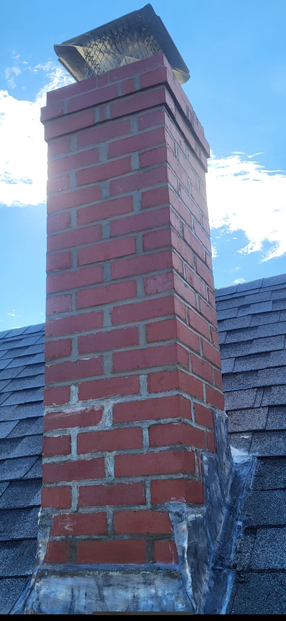 A brick chimney is sitting on top of a roof