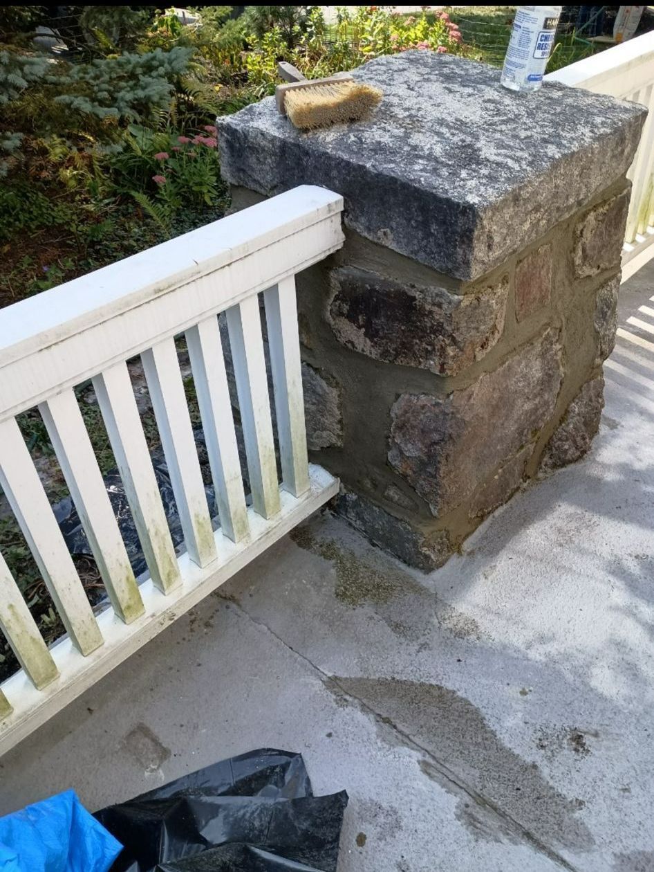 A white railing is sitting next to a large stone block