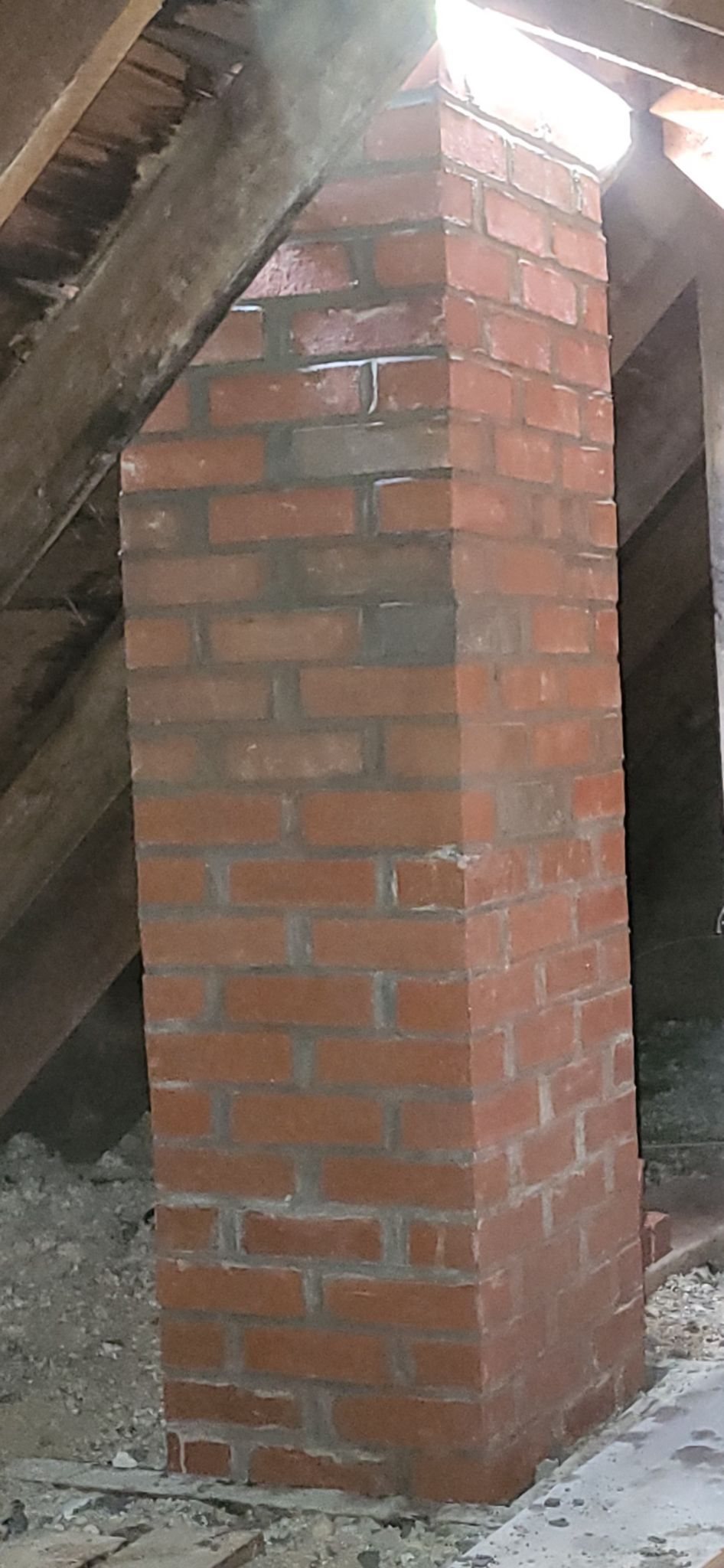 A brick chimney is sitting in the attic of a house